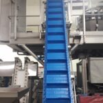 Cette image montre un convoyeur à bande modulaire conçu pour optimiser l'accumulation et le transport de produits, comme des cartons et des bacs, tout en s’adaptant aux contraintes spécifiques des environnements industriels. Sa structure modulaire permet de configurer facilement des courbes et des changements de niveaux pour répondre aux besoins particuliers de chaque installation. Résistant aux lavages à grandes eaux et à l’utilisation de produits désinfectants, ce convoyeur garantit des conditions de propreté et d’hygiène optimales, idéales pour les secteurs nécessitant des normes sanitaires rigoureuses. Polyvalent et durable, il permet aux entreprises d'améliorer la gestion des flux de production, en alliant efficacité et hygiène