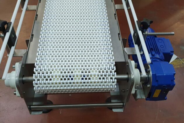 Cette image montre un convoyeur à bande modulaire conçu pour optimiser l'accumulation et le transport de produits, comme des cartons et des bacs, tout en s’adaptant aux contraintes spécifiques des environnements industriels. Sa structure modulaire permet de configurer facilement des courbes et des changements de niveaux pour répondre aux besoins particuliers de chaque installation. Résistant aux lavages à grandes eaux et à l’utilisation de produits désinfectants, ce convoyeur garantit des conditions de propreté et d’hygiène optimales, idéales pour les secteurs nécessitant des normes sanitaires rigoureuses. Polyvalent et durable, il permet aux entreprises d'améliorer la gestion des flux de production, en alliant efficacité et hygiène