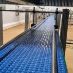 Convoyeur droit à bande modulaire, conçu pour répondre aux besoins de gestion de l'accumulation de produits tels que des cartons et des bacs, tout en s’adaptant aux spécificités de l’environnement industriel du client.