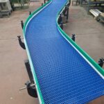 Convoyeur en "S" courbe à bande modulaire destiné à l'accumulation de produits dans une installation industrielle.