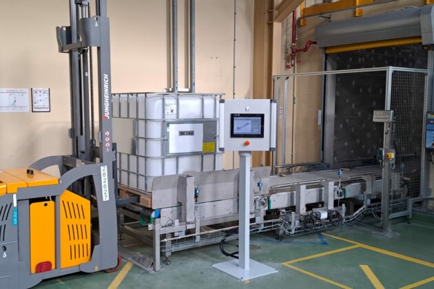 Ligne de convoyage de conteneurs IBC dans l'industrie chimique avec convoyeurs à chaînes à palettes métalliques.