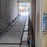 Ligne de convoyage de conteneurs IBC dans l'industrie chimique avec convoyeurs à chaînes à palettes métalliques.