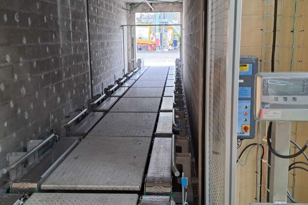 Ligne de convoyage de conteneurs IBC dans l'industrie chimique avec convoyeurs à chaînes à palettes métalliques.