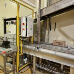 Ensemble robotisé associé à un convoyeur, conçu pour automatiser les tâches de dépalettisation et de décartonnage dans un environnement industriel.