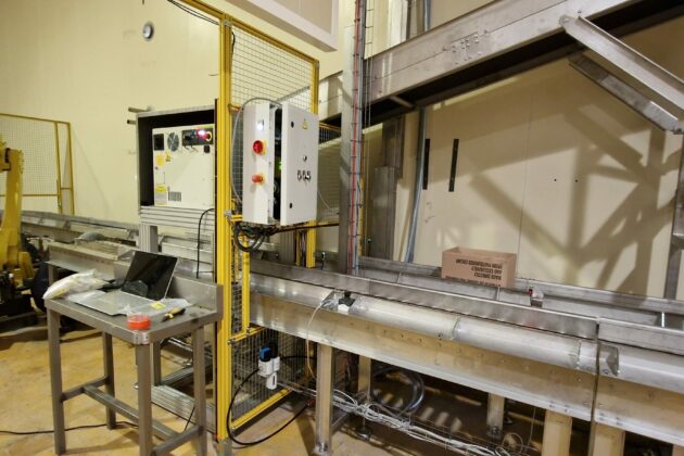 Ensemble robotisé associé à un convoyeur, conçu pour automatiser les tâches de dépalettisation et de décartonnage dans un environnement industriel.