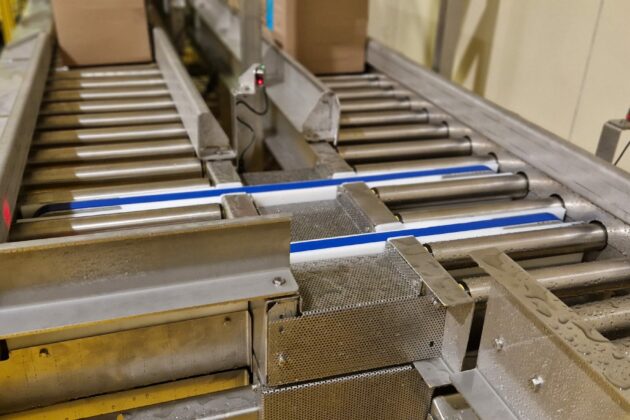 Convoyeurs à rouleaux intégrés avec des courroies de transfert latéral, optimisés pour la transition de cartons dans les environnements industriels.