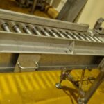 Portillon d'accès avec convoyeur à rouleaux motorisés, illustrant une solution d'automatisation pour le transport de produits